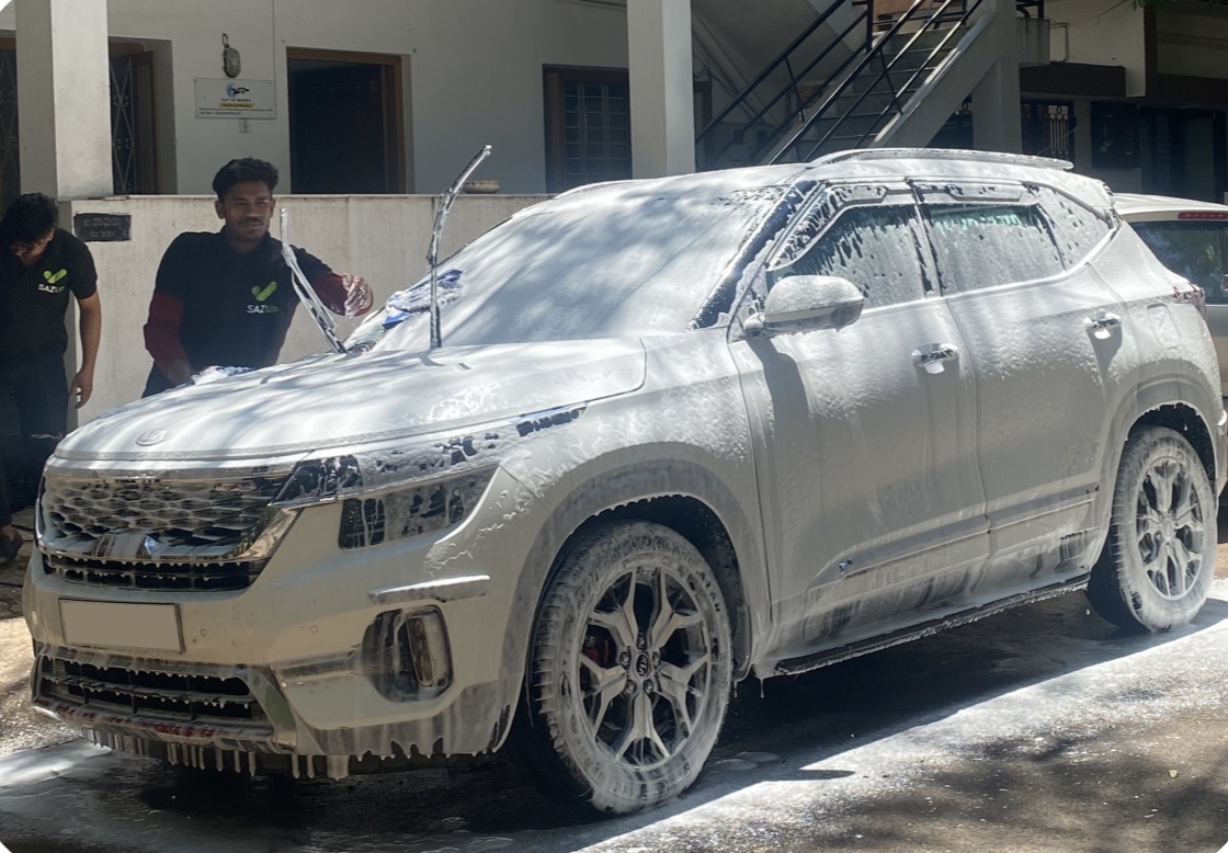 A SazUp detailer giving a white Kia Seltos a foam wash at the customer&rsquo;s doorstep in Bangalore